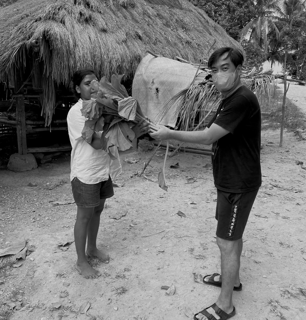 Edward Chen sharing vegetables from the garden with a villager